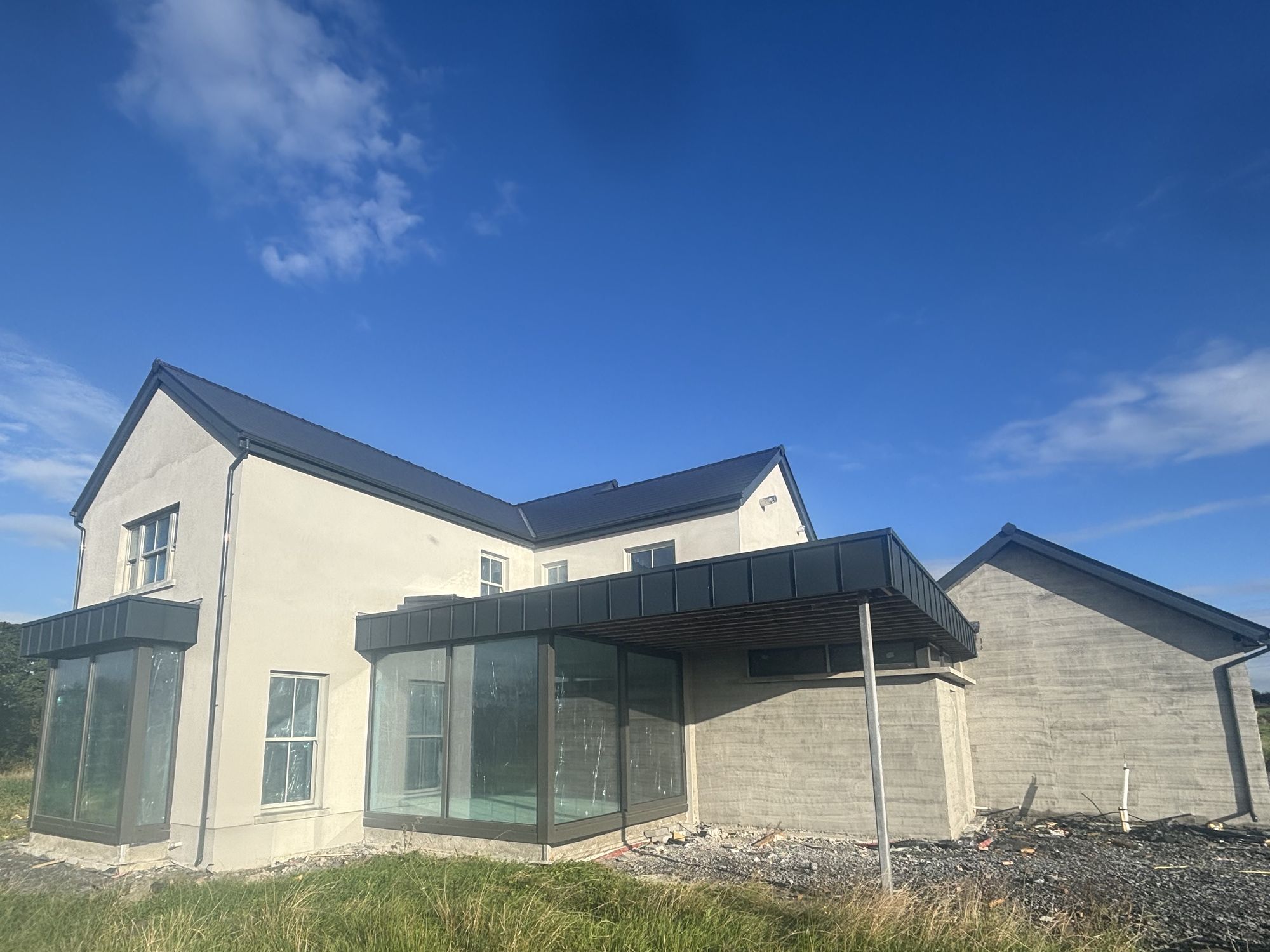 Finished modern two-storey house with a glazed corner under a blue sky